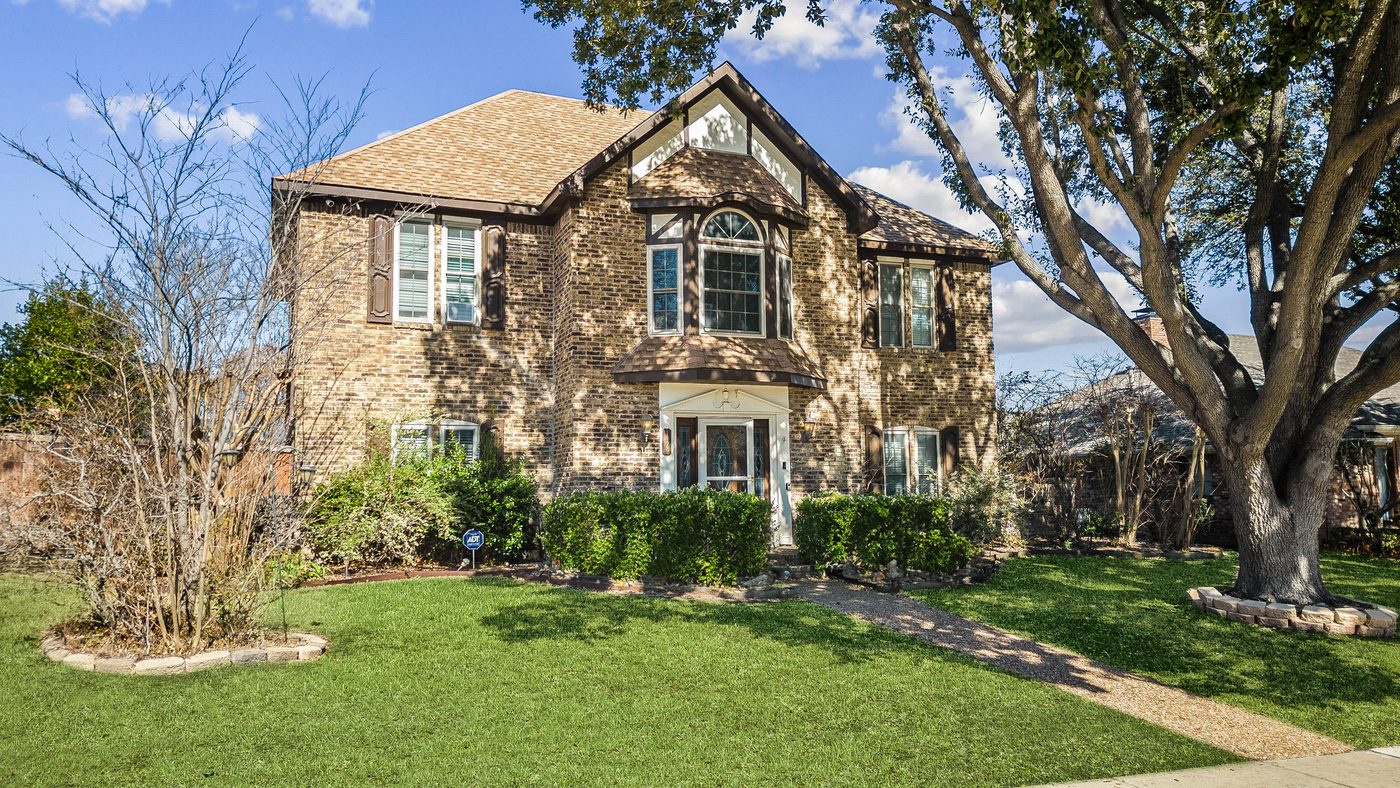 Two-story brick front of Baffin Bay with a large oak tree and lawn