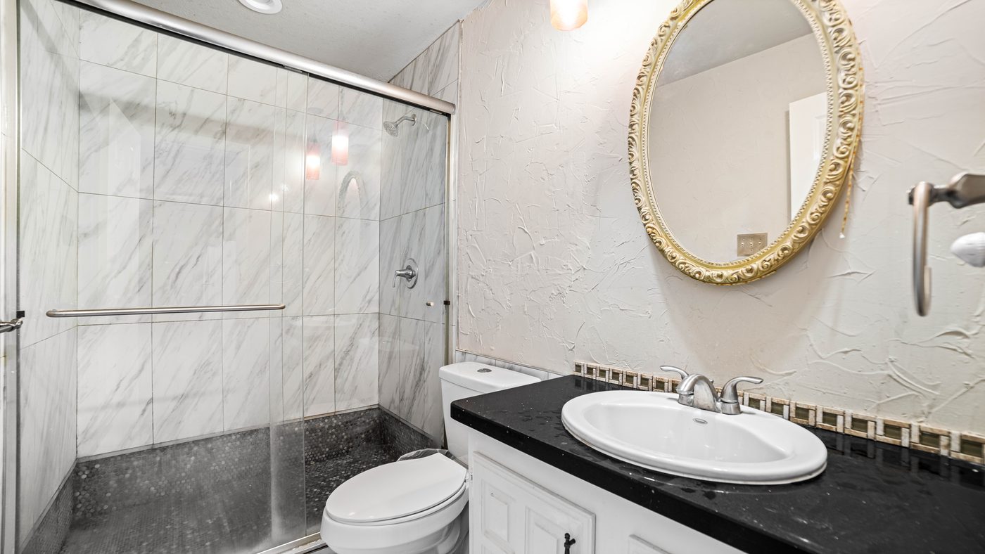 Bathroom with glass shower and round mirror at Chinaberry