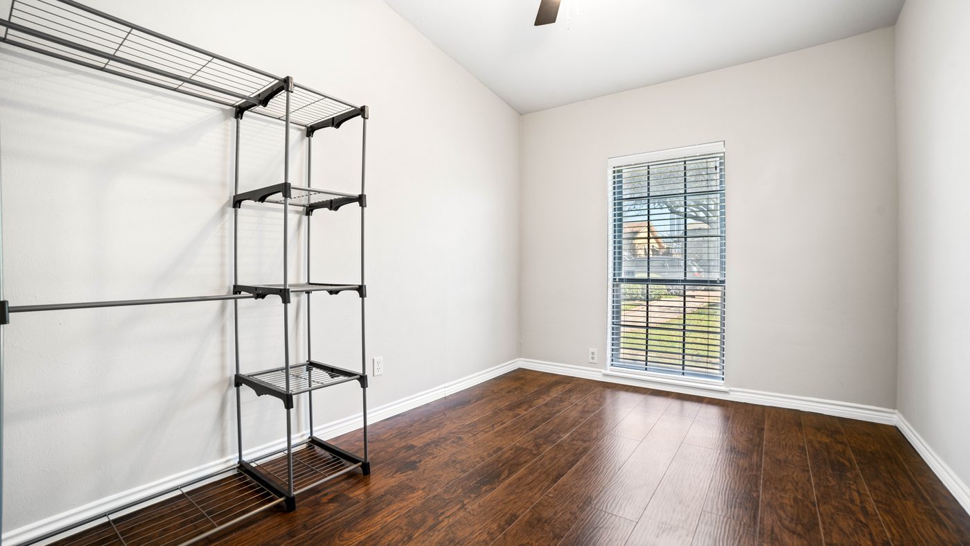Bedroom with wood-look floor, window and garment rack at Chinaberry