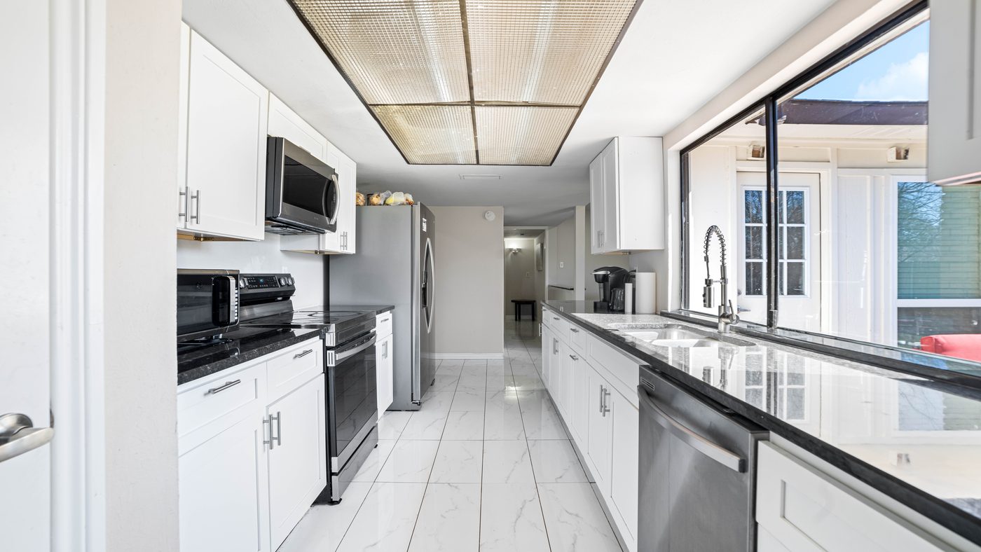 Galley kitchen with white cabinets and picture window at Chinaberry