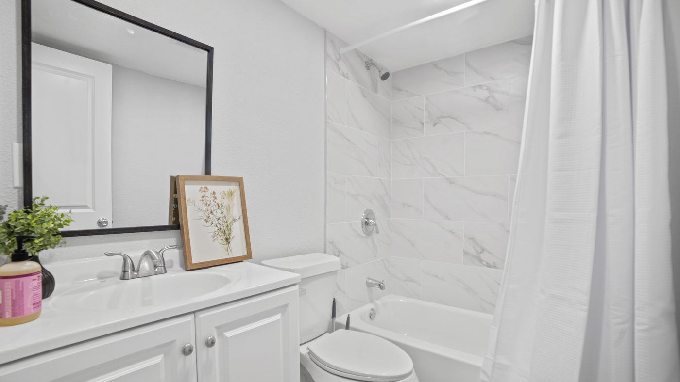Bathroom with white vanity and marble-look tub surround at John Muir