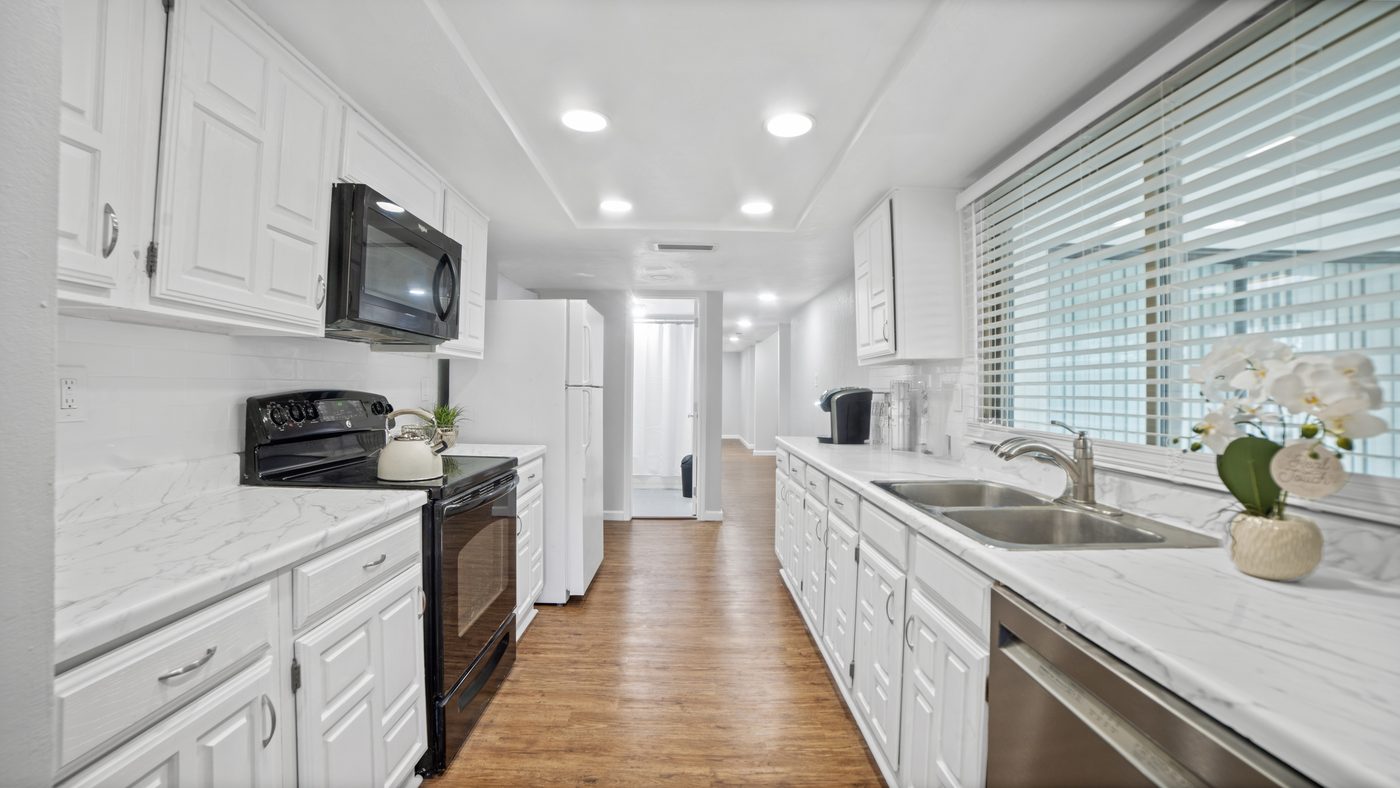 Galley kitchen with white cabinets and marble-look counters at John Muir