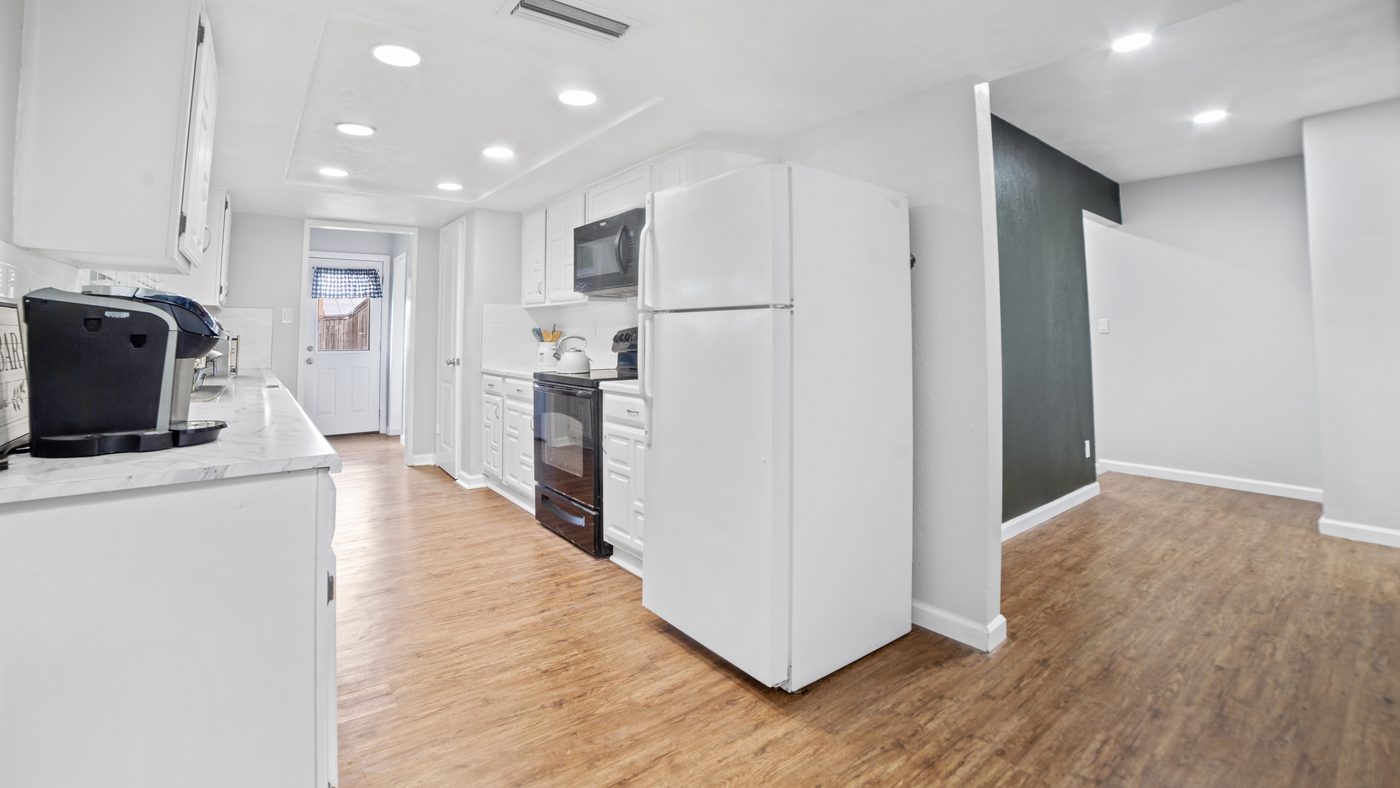Kitchen with white refrigerator and wood-look floor at John Muir
