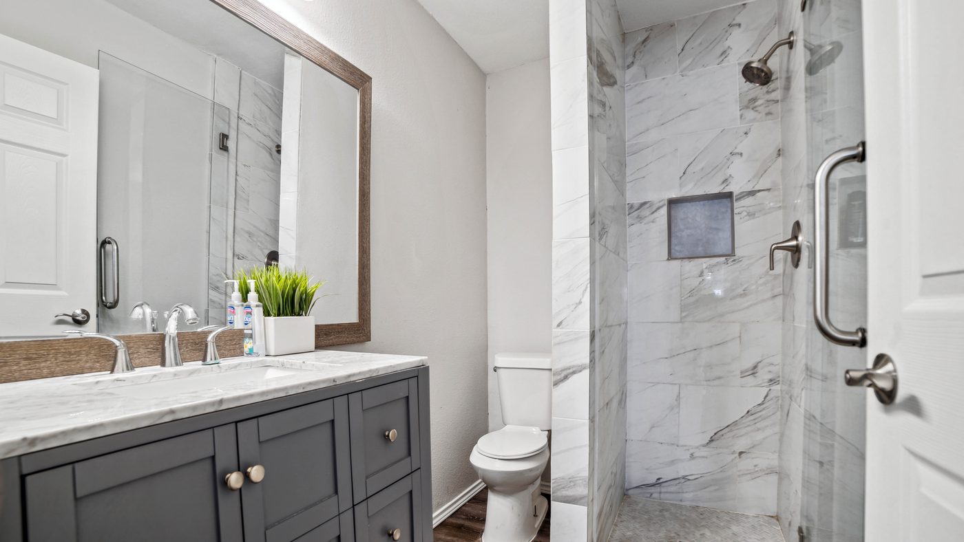 Bathroom with gray vanity and marble-look shower at Overdowns
