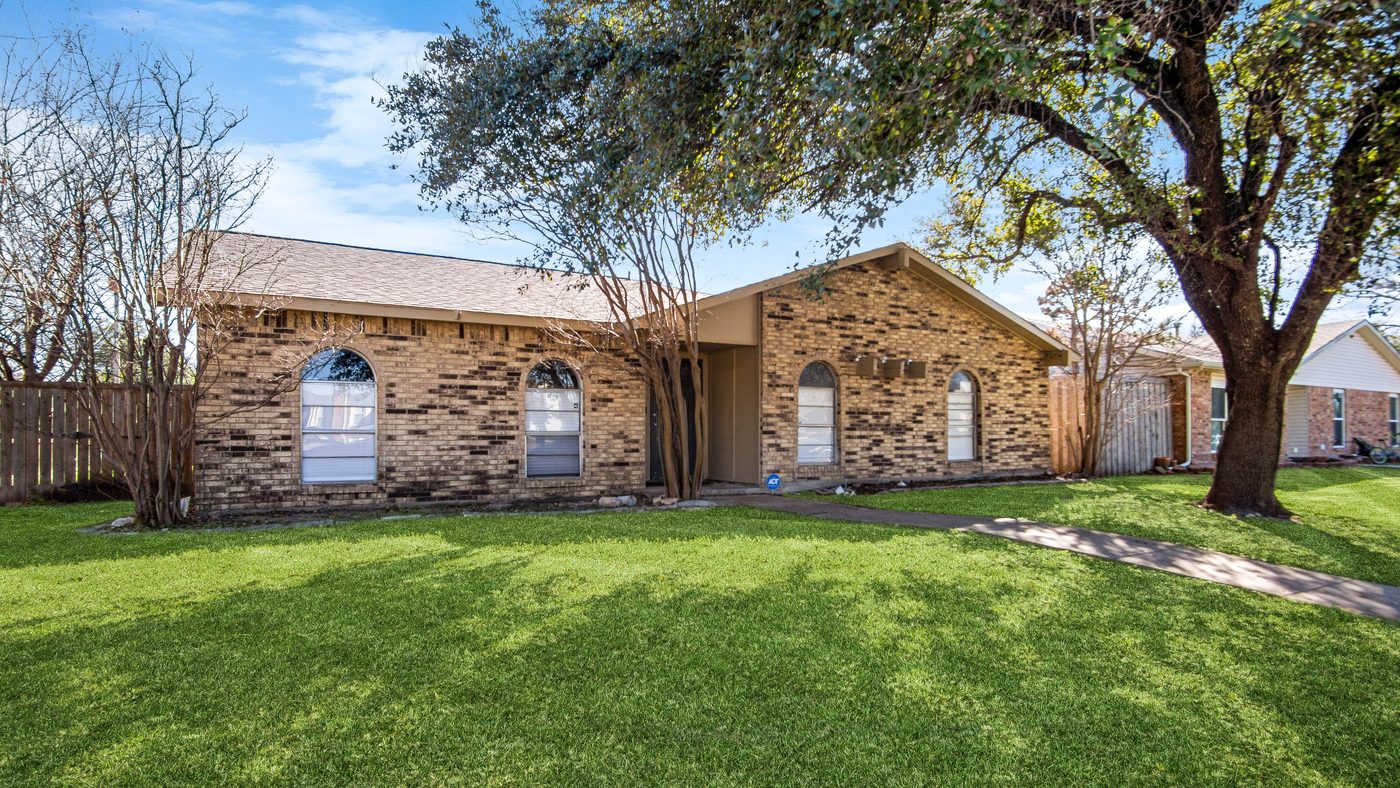 Brick front of Spring Creek with arched windows and a shade tree