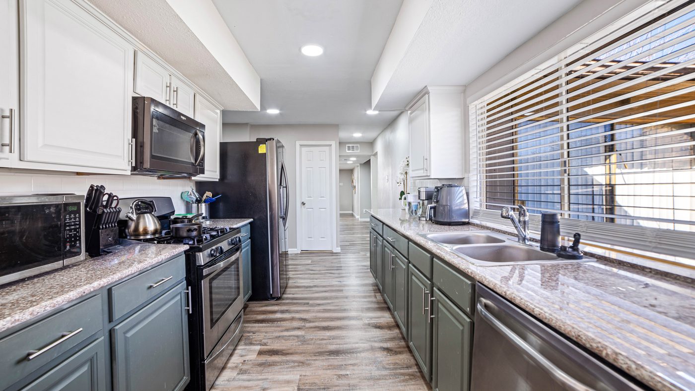 Galley kitchen with green cabinets and granite counters at Spring Creek