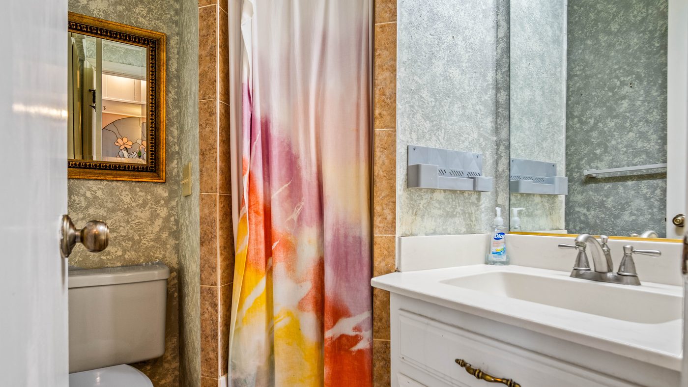 Bathroom with vanity and colorful shower curtain at Stain Glass