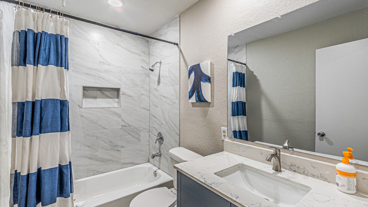 Bathroom with marble-look tub surround and striped curtain at Yosemite